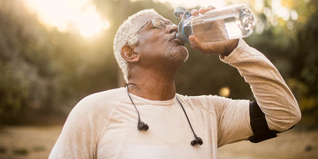 Elderly jogging man drinking from water bottle Elderly jogging man drinking from water bottle